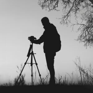 Silhouette of a photograpfer with a tripod and its equipment in a misty countryside