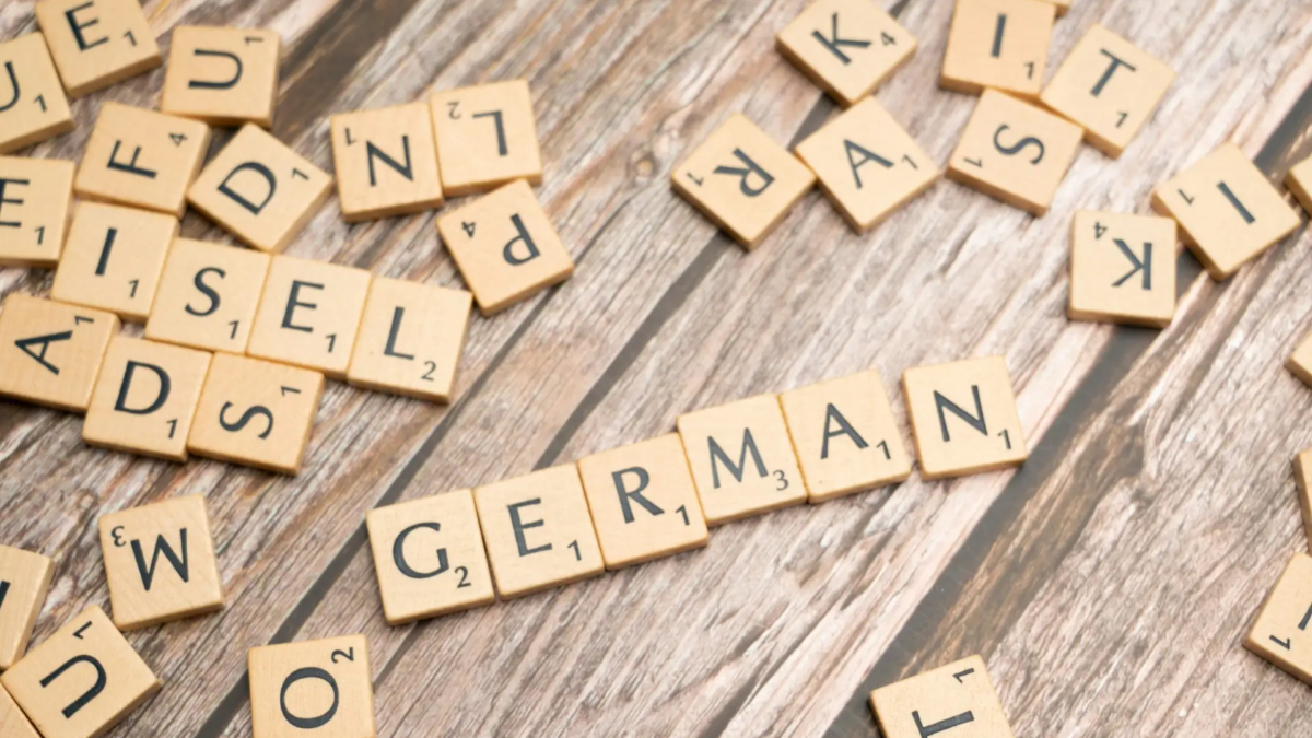 Wooden letter tiles spelling the word 'German' on a table, representing the journey where I am improving my German through learning and daily practice.