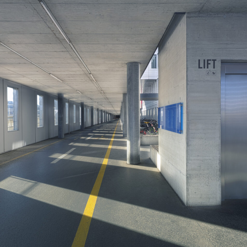 Architecture photography of the Jacob Burckhardt Haus in Basel showing a long corridor with lift, strong perspective lines and afternoon light and shadow patterns. Architekturfotografie des Jacob Burckhardt Haus in Basel mit einem langen Korridor, Lift und starken Fluchtlinien im Nachmittagslicht. Alan Philip Muller